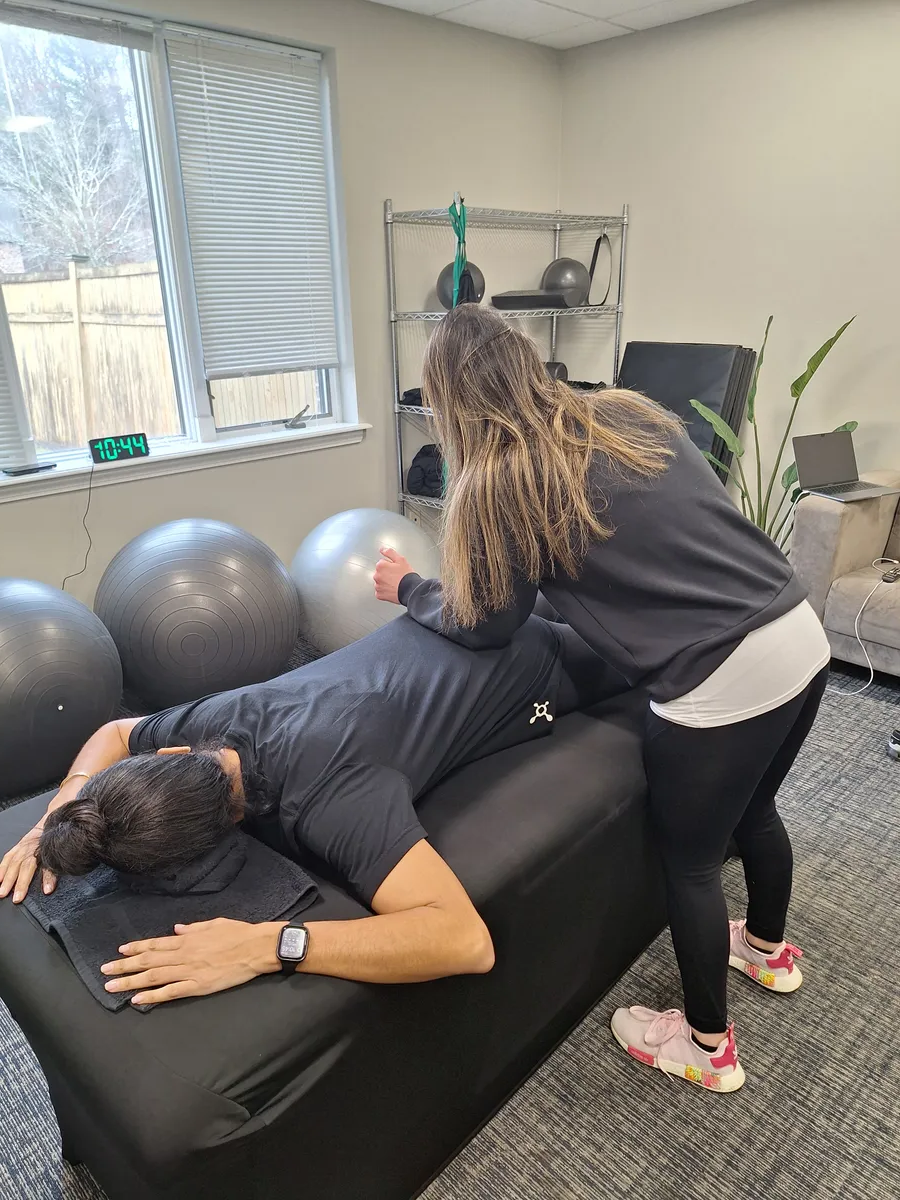 woman sitting on black chair in front of glass-panel window with white curtains